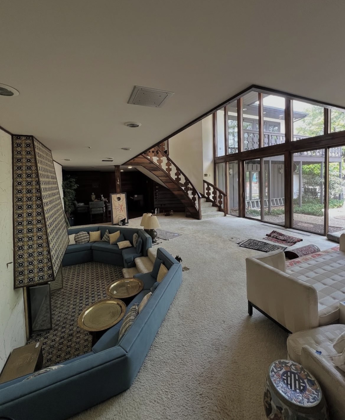 Large open-plan living room with sofas, tables, and a curved staircase
