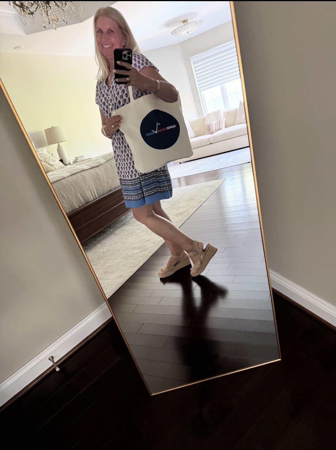 A customer taking a mirror photo with a natural canvas Super Sonic Loads tote